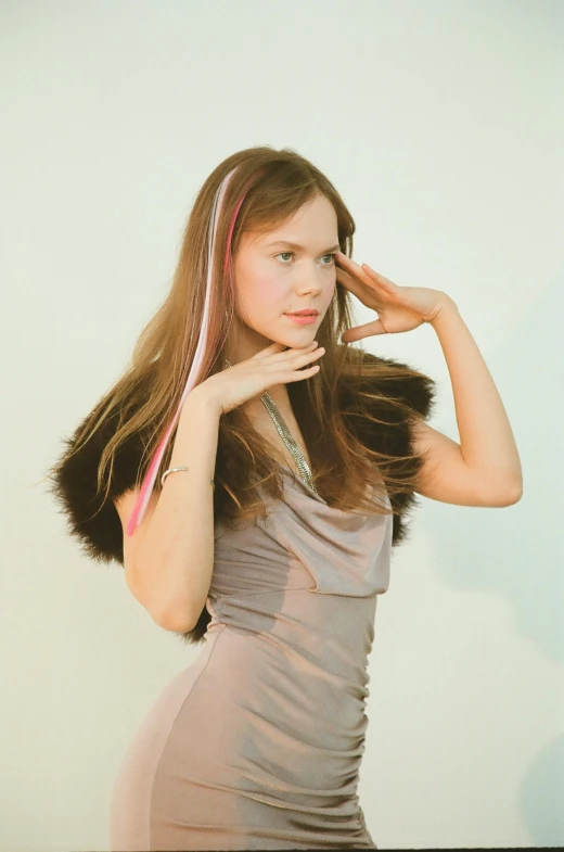 a woman in a gray dress posing for a picture, an album cover, inspired by Louisa Matthíasdóttir, brown long and straight hair, with pastel pink highlights, hands in her hair. side-view, ribbon in her hair