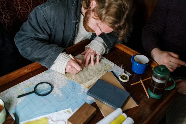 a couple of people that are sitting at a table, pexels contest winner, arts and crafts movement, nautical maps, adventurer, drawing sketches on his notebook, avatar image