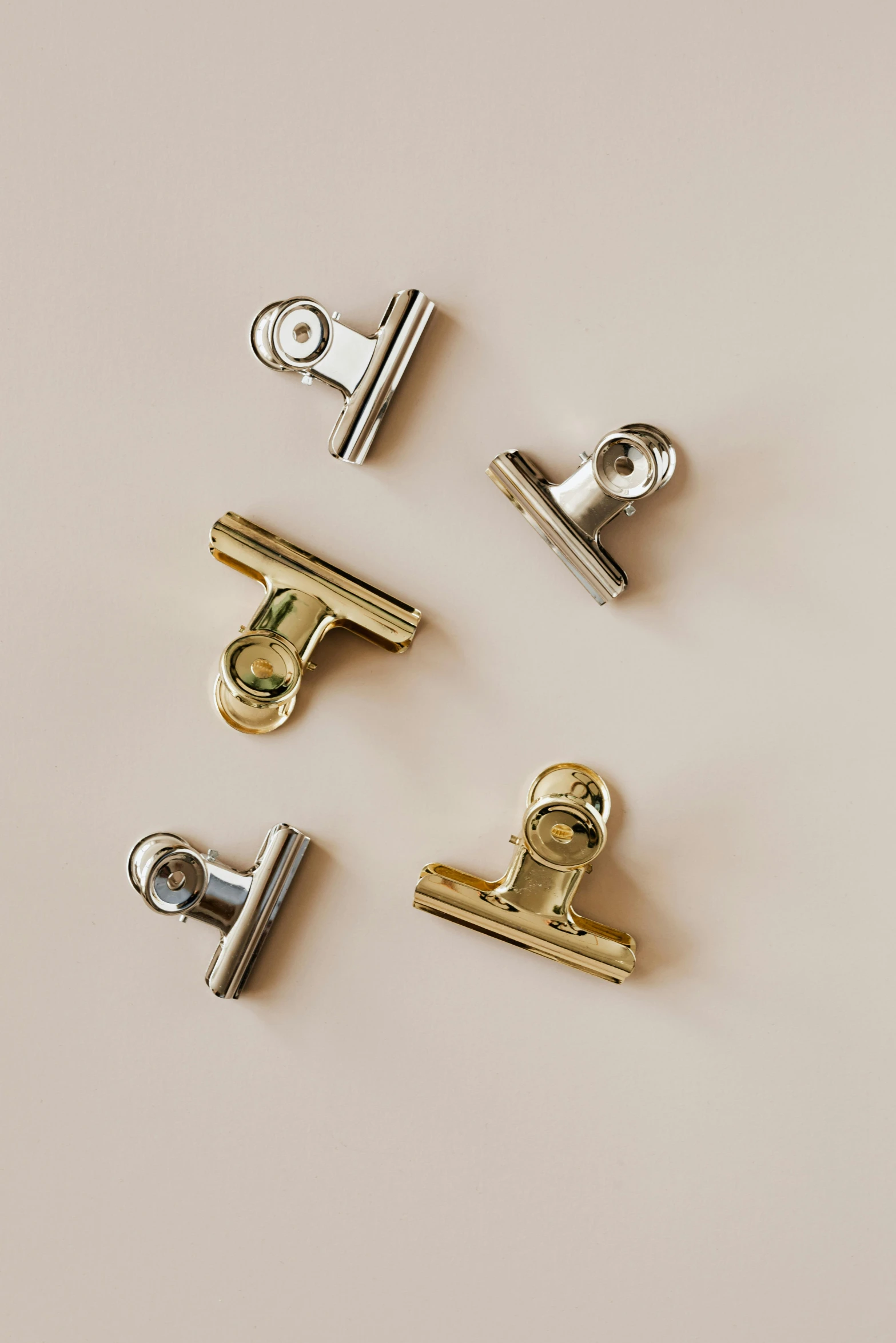 a group of metal clips sitting on top of a white surface, a picture, by Nina Hamnett, unsplash, accented in bright metallic gold, official product image, wall, silver with gold trim