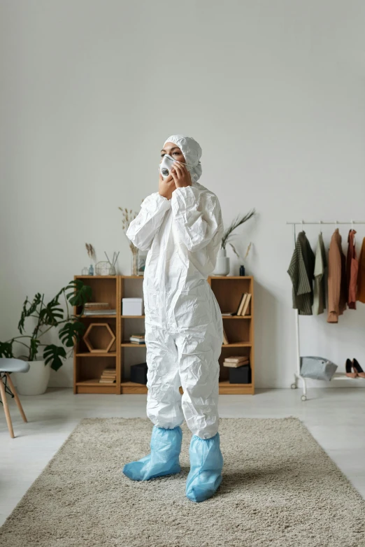 a man in a protective suit talking on a cell phone, an album cover, pexels contest winner, standing in corner of room, white puffy outfit, female investigator, full body sarcastic pose