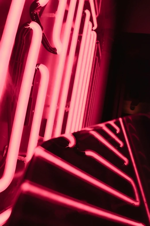 a red neon sign hanging from the side of a building, by Doug Ohlson, unsplash, process art, glowing heating coils, ((pink)), up close, neon basement