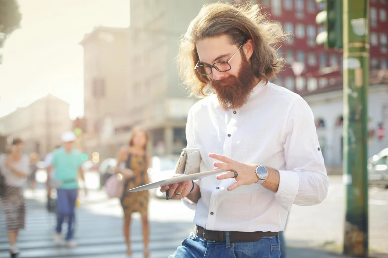 a man with a beard using a tablet computer, a photo, trending on unsplash, walking to the right, wearing a linen shirt, ginger bearded man with glasses, mid long hair