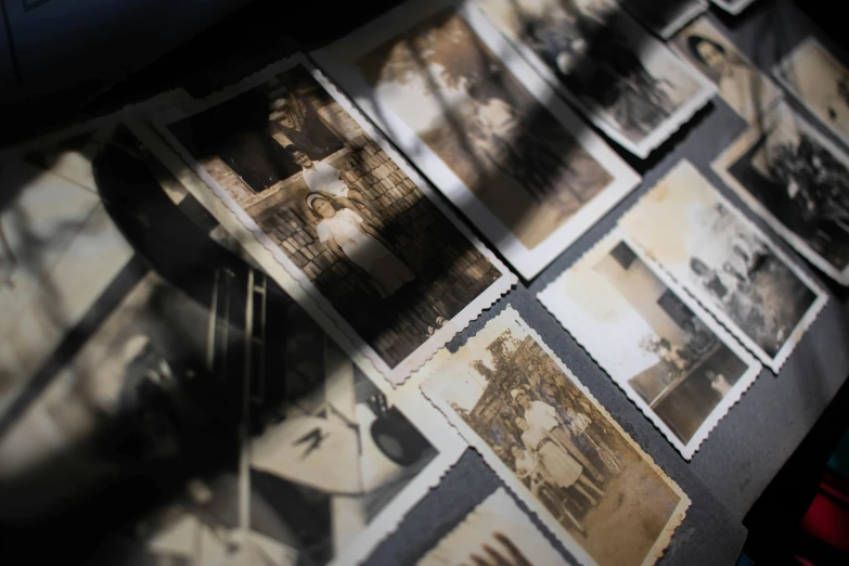 a bunch of old photos sitting on top of a table, unsplash, shadowy figures, high angle close up shot, national archives, high quality photo