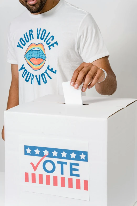 a man putting a vote in a box, trending on reddit, white and teal garment, cardboard cutout, promo image, wearing a shirt