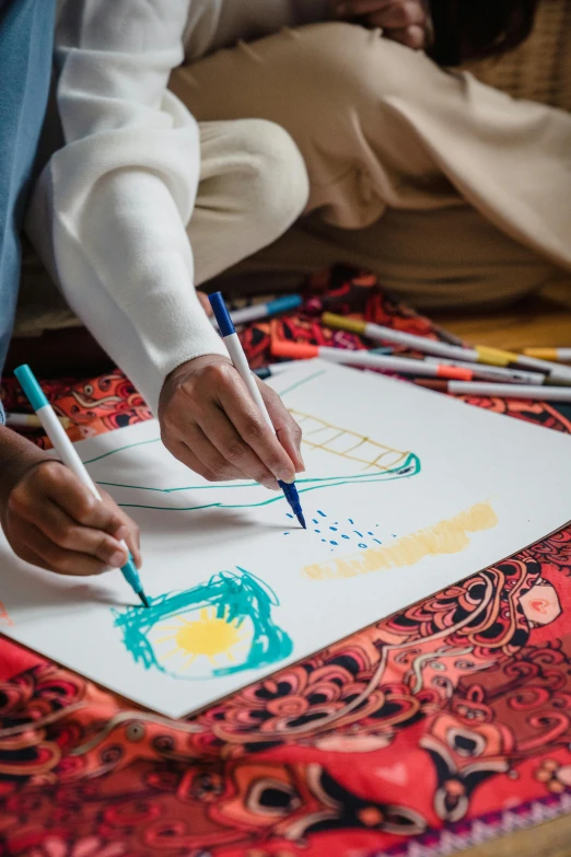 a person is drawing on a piece of paper, a child's drawing, trending on pexels, process art, islamic art, a painting of two people, primary colors are white, holding paintbrushes