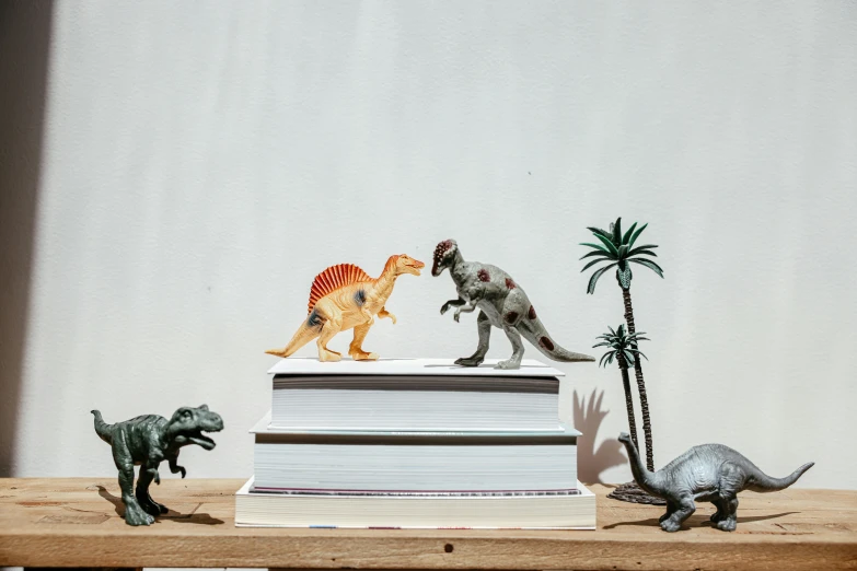 a stack of books sitting on top of a wooden table, a statue, by Adam Rex, trending on pexels, dinosaurs, pvc figurine, triceratops, full body image