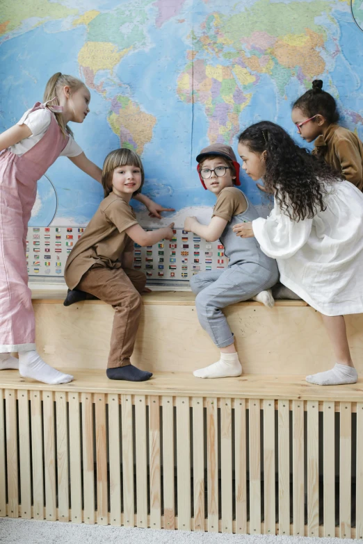 a group of children sitting on a bench in front of a world map, inspired by Elsa Beskow, pexels contest winner, interactive art, standing in class, reaching out to each other, slide show, standing on a desk