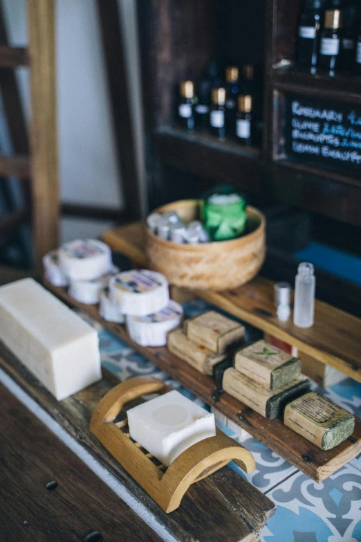 a counter topped with lots of different types of soap, unsplash, renaissance, cheeses, on wooden table, square, travel