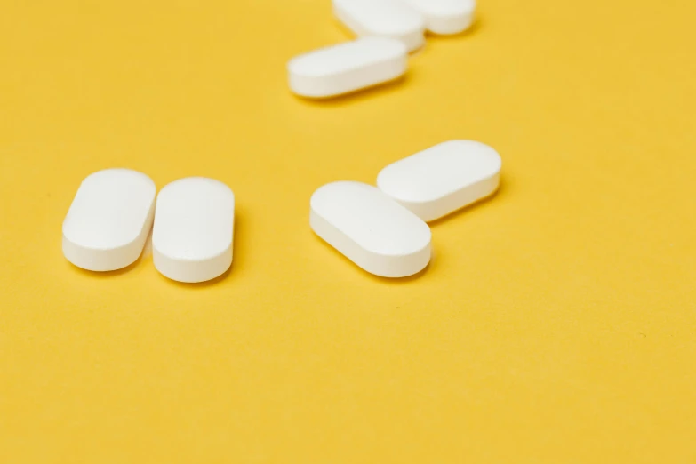 white pills on a yellow background, by Whitney Sherman, pexels, antipodeans, white panels, broad shoulder, on a white table, finely illustrated