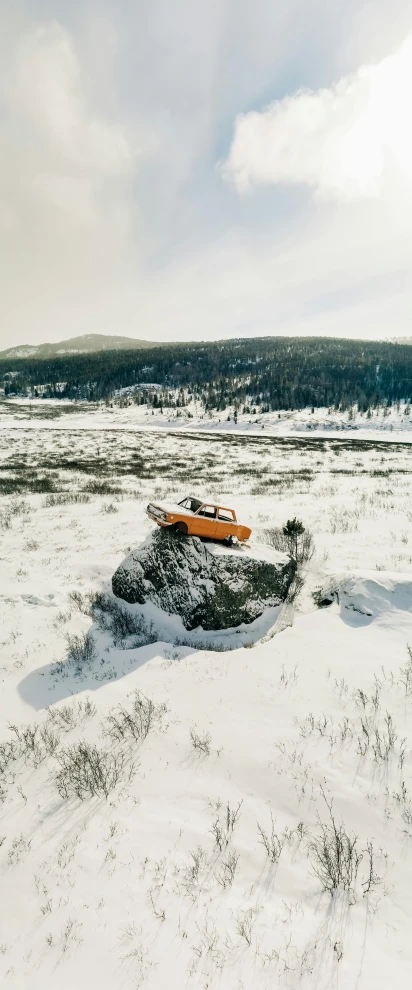 a man riding a snowboard down a snow covered slope, an album cover, by Haukur Halldórsson, pexels contest winner, land art, old abandoned car sinking, white and orange, medium format color photography, high vantage point