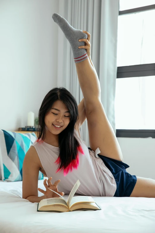 a woman laying on a bed reading a book, inspired by helen huang, happening, standing athletic pose, taking a selfie, contorted limbs, wearing shorts and t shirt