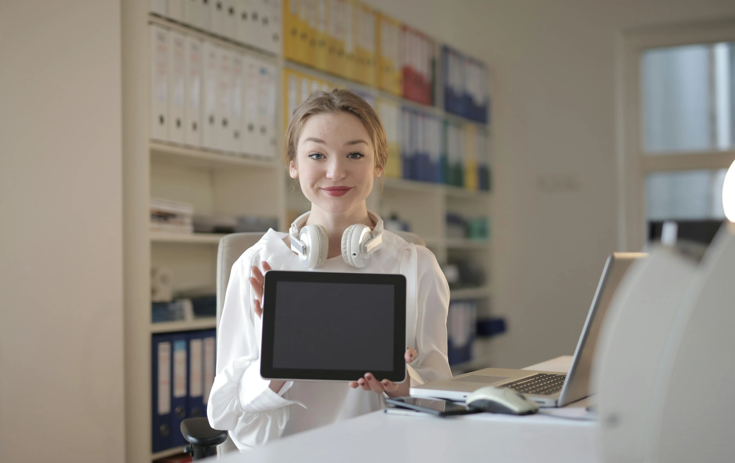 a woman in a white shirt holding a tablet computer, pexels, in an call centre office, posing for a picture, standing on a desk, uploaded