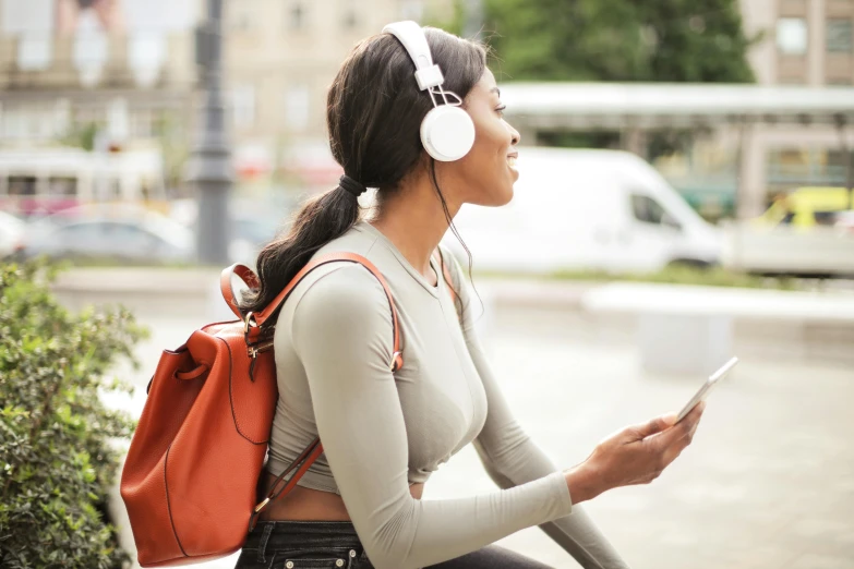 a woman sitting on a bench with headphones on, trending on pexels, essence, walking down, student, displayed