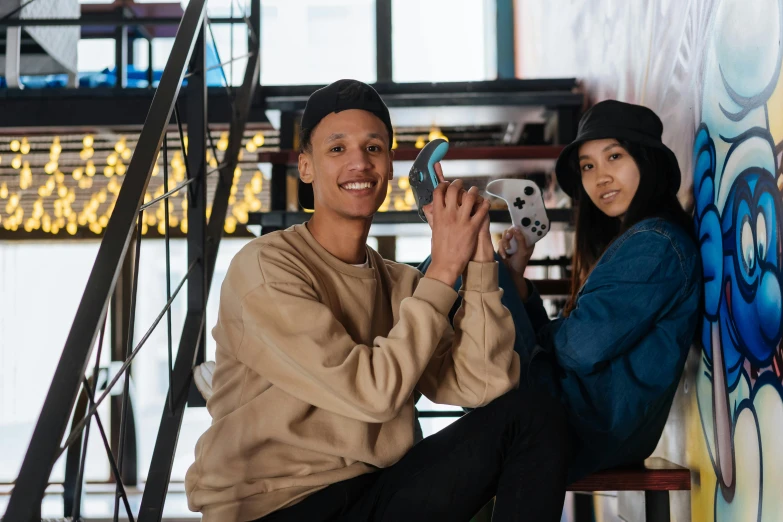 a man and a woman sitting next to each other, pexels contest winner, realism, style of tony hawk pro skater, holding controller, teenager hangout spot, official store photo