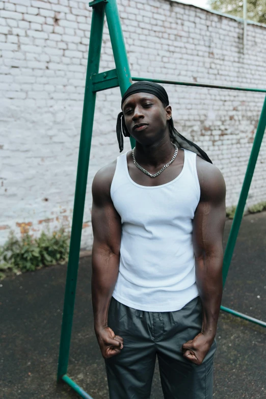 a man standing in front of a green swing, an album cover, inspired by Terrell James, trending on pexels, renaissance, tight fitted tank top, portrait mode photo, british gang member, muscular! white