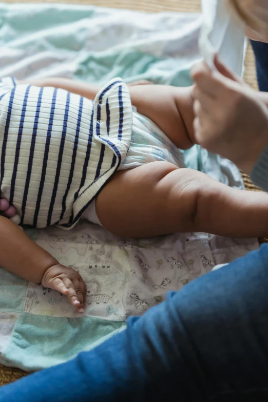 a baby laying on top of a blanket next to a woman, pexels contest winner, happening, thighs, young boy, blue print, loosely cropped