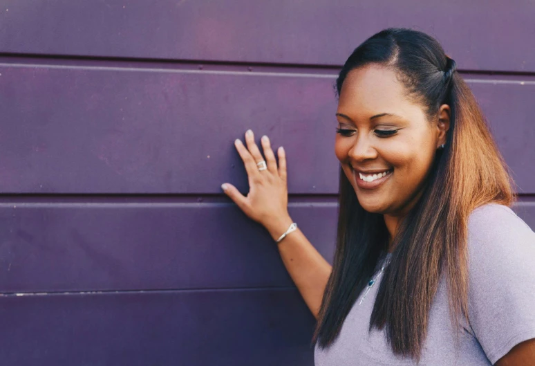 a smiling woman leaning against a purple wall, pexels contest winner, happening, african american girl, her hair is long and straight, instagram post, purple metal ears