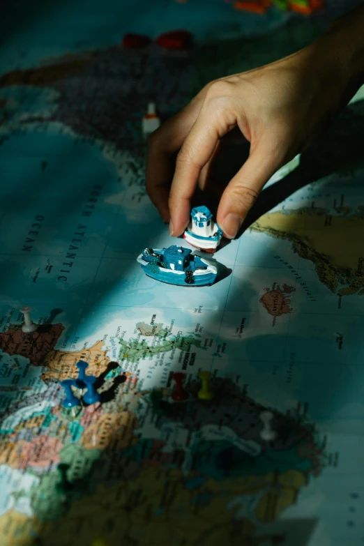 a close up of a person's hand on a map, a jigsaw puzzle, by Adam Marczyński, trending on unsplash, tiny ships docking, toy photo, blue, tiny spaceship