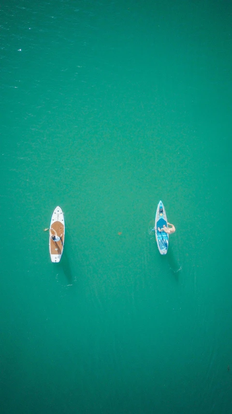 a couple of boats floating on top of a body of water, sup, top down shot, thumbnail, teal