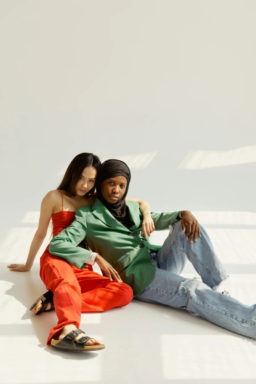 a man and a woman sitting next to each other, an album cover, by Gavin Hamilton, trending on pexels, green corduroy pants, james jean and fenghua zhong, at a fashion shoot, mix of ethnicities and genders