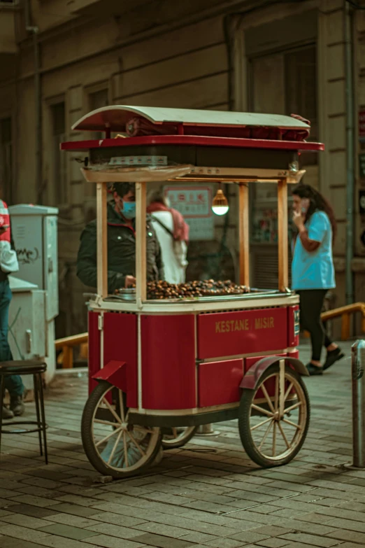 a red cart sitting on top of a wooden floor, a colorized photo, by Elsa Bleda, pexels contest winner, food stalls, ottoman sultan, early evening, movie still 8 k