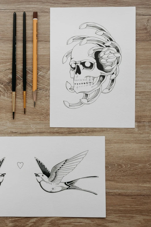 a couple of cards sitting on top of a wooden table, an ink drawing, by Lucas Vorsterman, trending on pexels, skull tattoo, line art colouring page, hyperrealistic sparrows, tattoo sketch of a ocean