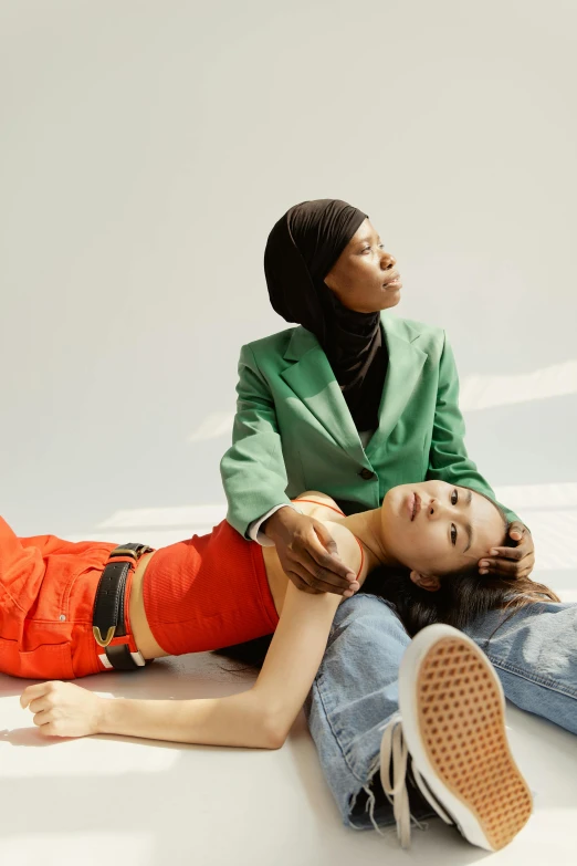 a couple of women laying on top of each other, an album cover, inspired by Fei Danxu, trending on pexels, muslim, at a fashion shoot, hito steyerl, wearing green clothing