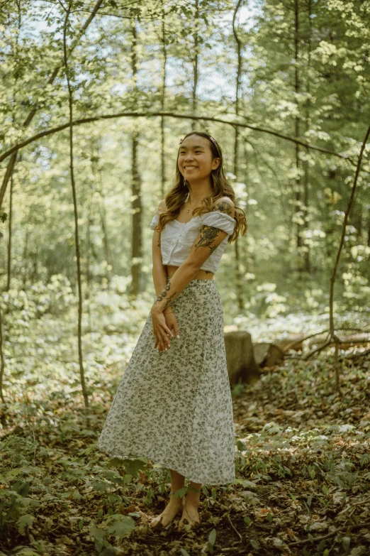 a woman standing in the middle of a forest, wearing a tanktop and skirt, smiling, forest themed, vines