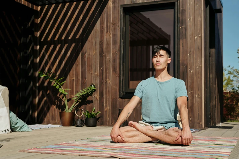 a man sitting in the middle of a yoga pose, a portrait, unsplash, shin hanga, standing outside a house, full daylight, ambient vibe, carefully crafted