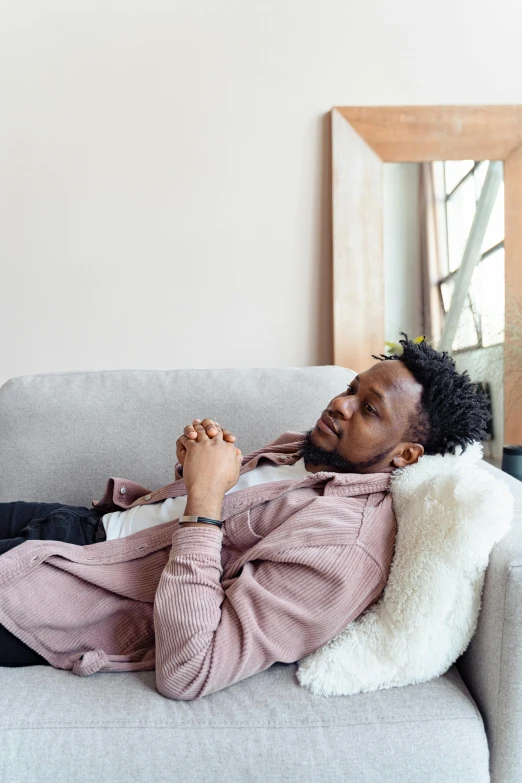 a man laying on a couch in a living room, trending on unsplash, romanticism, african aaron paul, contemplative, romantic lead, ignant