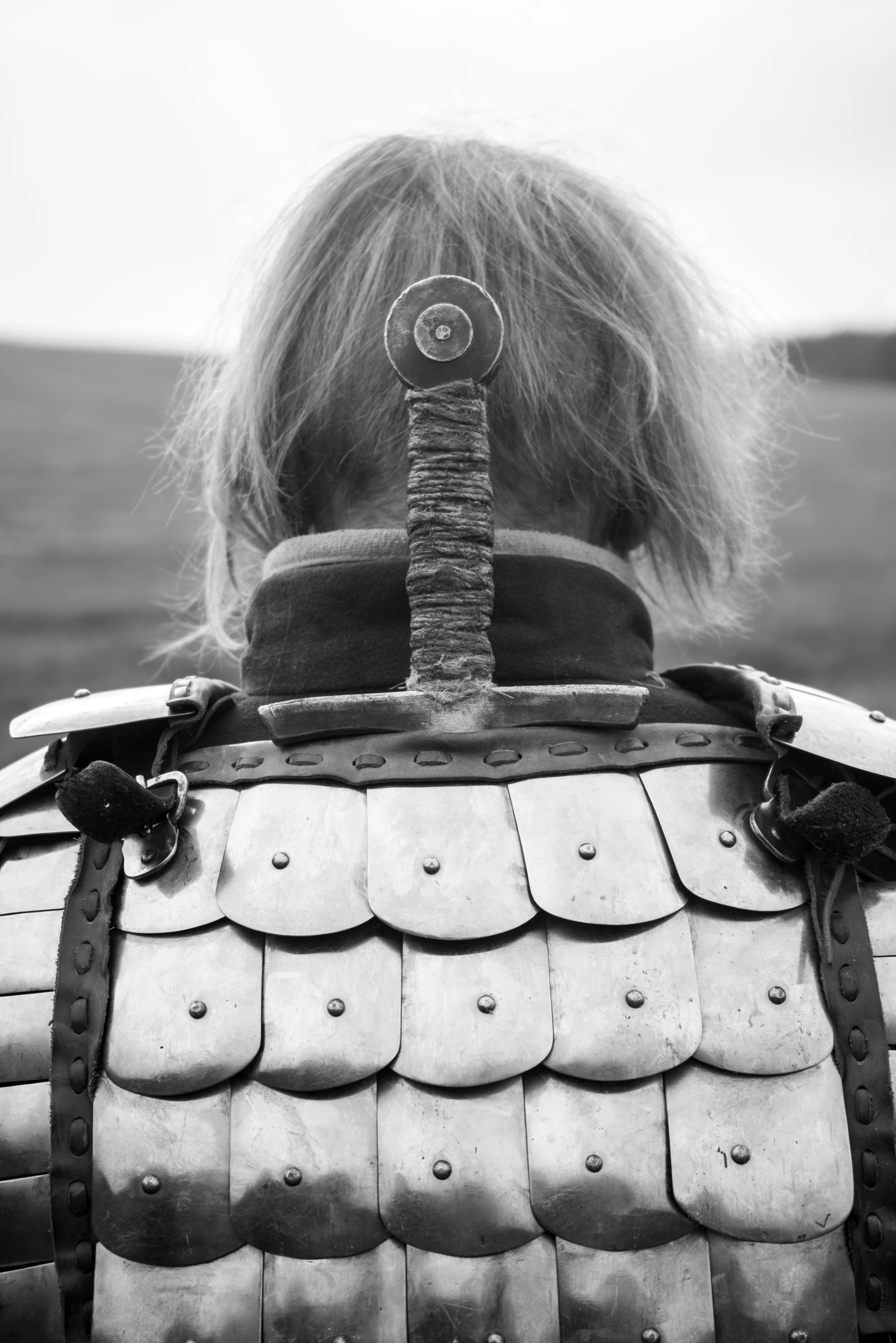 a black and white photo of a man in armor, an album cover, inspired by Kanō Sanraku, unsplash, shot from behind blades of grass, shoulder pads, historical reenactment, trending photo