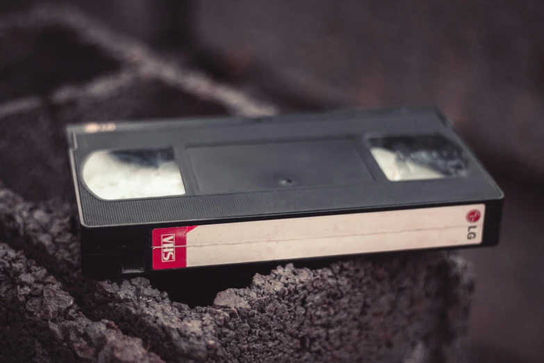 a video cassette sitting on top of a rock, inspired by Elsa Bleda, unsplash, film burn, netflix trese, bad vhs, historical picture