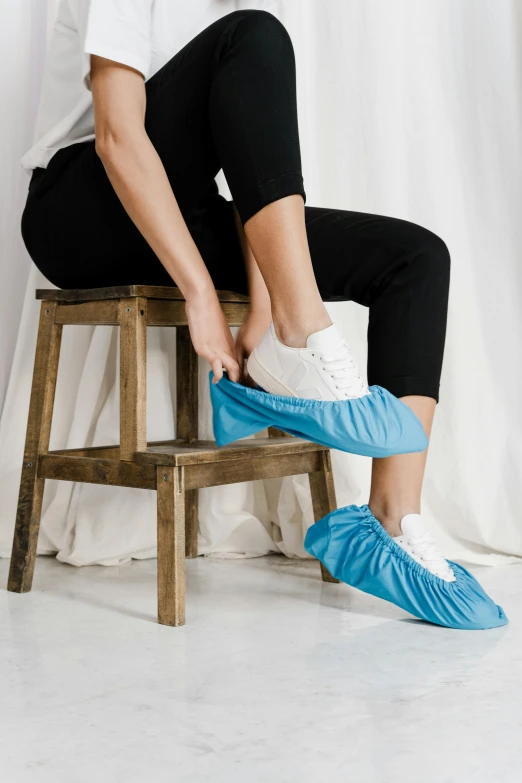 a woman sitting on top of a wooden stool, blue shoes, made of lab tissue, thumbnail, premium