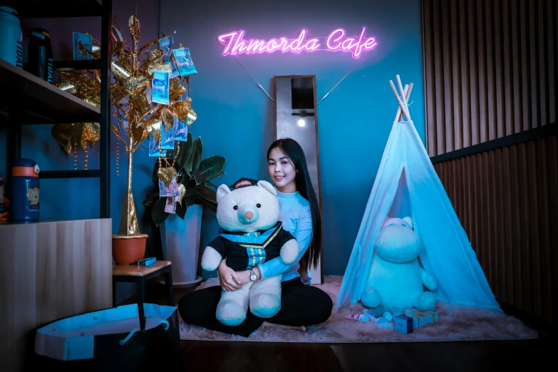 a woman sitting on the floor holding a teddy bear, a cartoon, temporary art, neon blue color, miniature cafe diorama, tiffany style, teepee