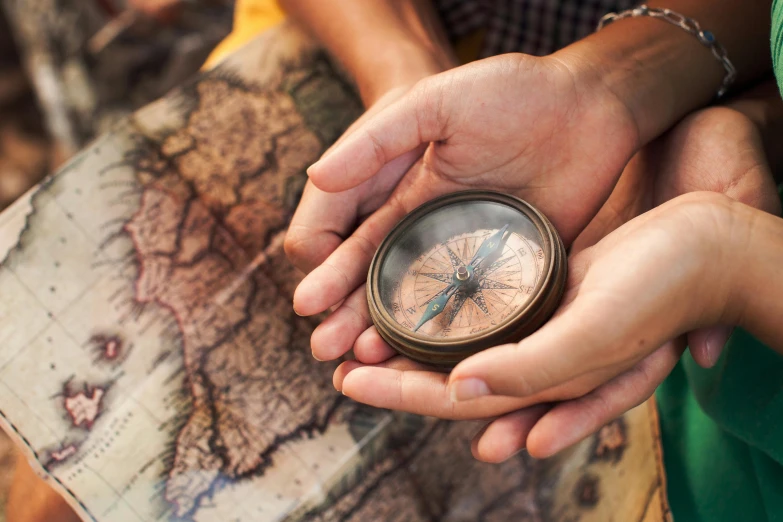 a close up of a person holding a compass, trending on pexels, avatar image, brown, national geograpic, multiple stories