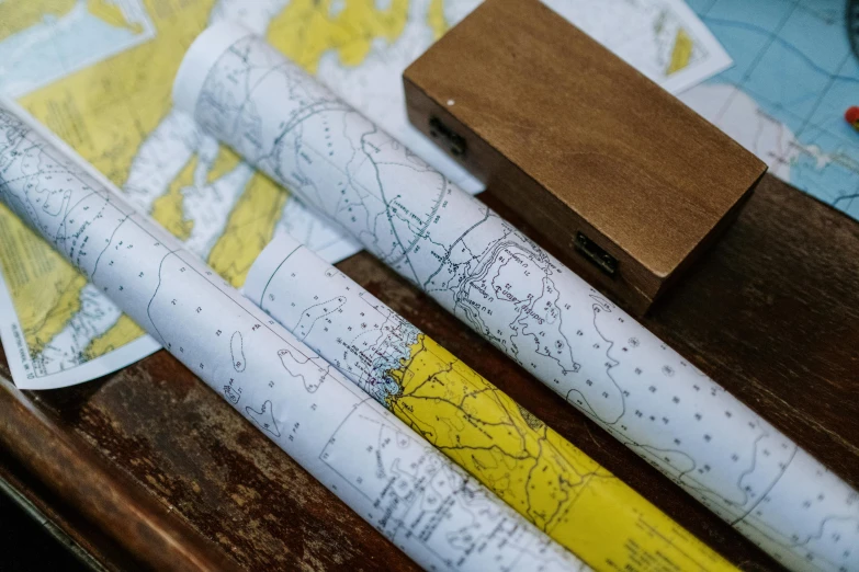 a couple of pens sitting on top of a wooden table, by Helen Stevenson, happening, nautical maps, yellow, close up photograph, wallpapers