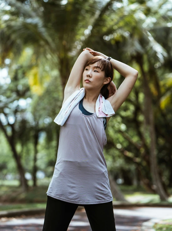 a woman stretching her arms in a park, unsplash, happening, wearing : tanktop, malaysian, wearing a towel, profile image