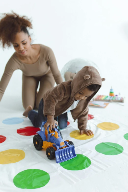 a woman and a child playing with a toy truck, pexels contest winner, twister, crawling, colored dots, 64x64