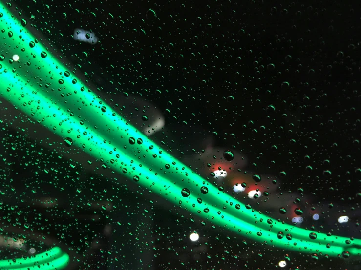 a close up of a car window with raindrops on it, inspired by Bruce Munro, unsplash, holography, green neon signs, lined with neon tube lights, aqua volumetric lights, green concert light