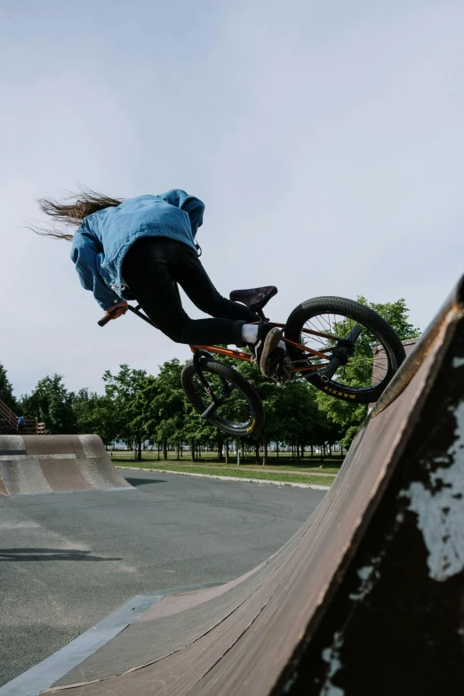 a person riding a bike up the side of a ramp, at a skate park, kailee mandel, riding in the sky, paisley