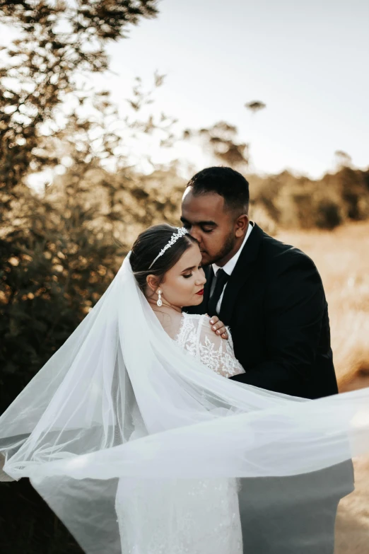 a bride and groom standing next to each other in a field, by Elizabeth Durack, pexels contest winner, laying down, lace veil, diverse, formal wear