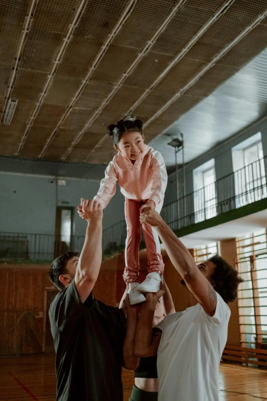 a man holding a baby up in the air, a colorized photo, inspired by The Family Circus, pexels contest winner, young asian girl, in the high school gym, lofi, boys