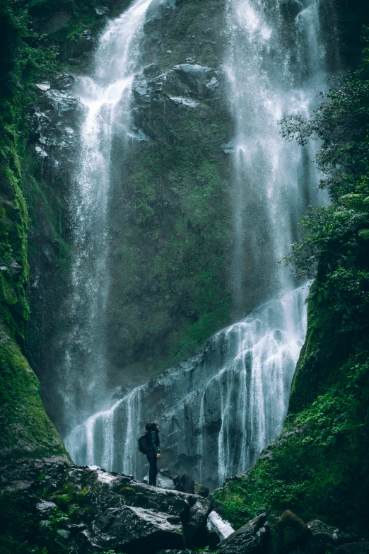 a person standing in front of a waterfall, by Elsa Bleda, renaissance, andes mountain forest, te pae, lush valley, we go