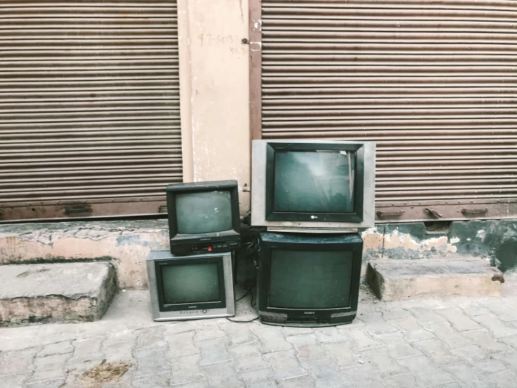 a group of televisions sitting in front of a building, unsplash, serial art, crusty electronics, crt tubes, instagram post, old furnitures