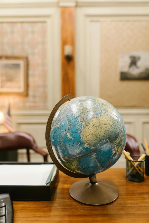 a globe sitting on top of a desk next to a calculator, a portrait, by Joe Stefanelli, in the oval office, map, thumbnail, cinematic shot