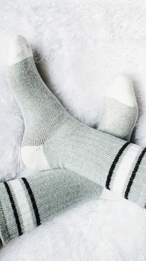 a pair of socks laying on top of a white blanket, inspired by Sarah Lucas, trending on pexels, grey and silver, striped, sporty, husky