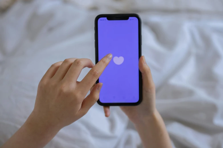 a close up of a person holding a cell phone, white bed, ((purple)), (heart), screen tones