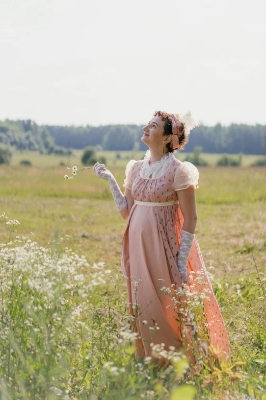 a woman in a pink dress standing in a field, an album cover, inspired by Cassandra Austen, pexels, traditional russia, maternity feeling, delightful, movie still