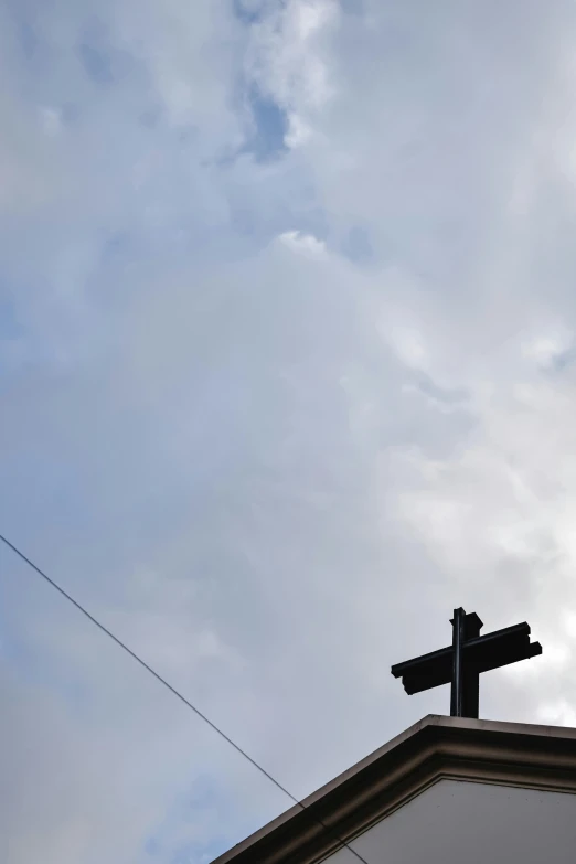 a cross on top of a building under a cloudy sky, by Carey Morris, street signs, low quality photo, single image