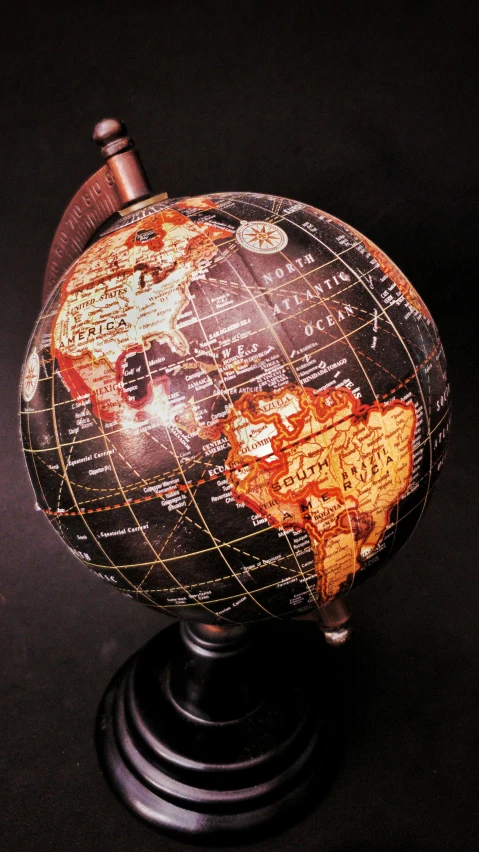 a close up of a globe on a stand, black and terracotta, on a black background, multi - coloured, high detailed print